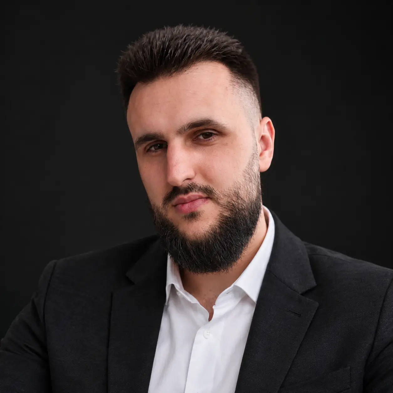 Kamber Kamberović, Kambo, portrait in a dark jacket and white shirt, on a dark background
